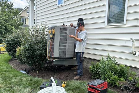 HVAC technicians servicing residential air conditioning unit HVAC technicians servicing residential air conditioning unit